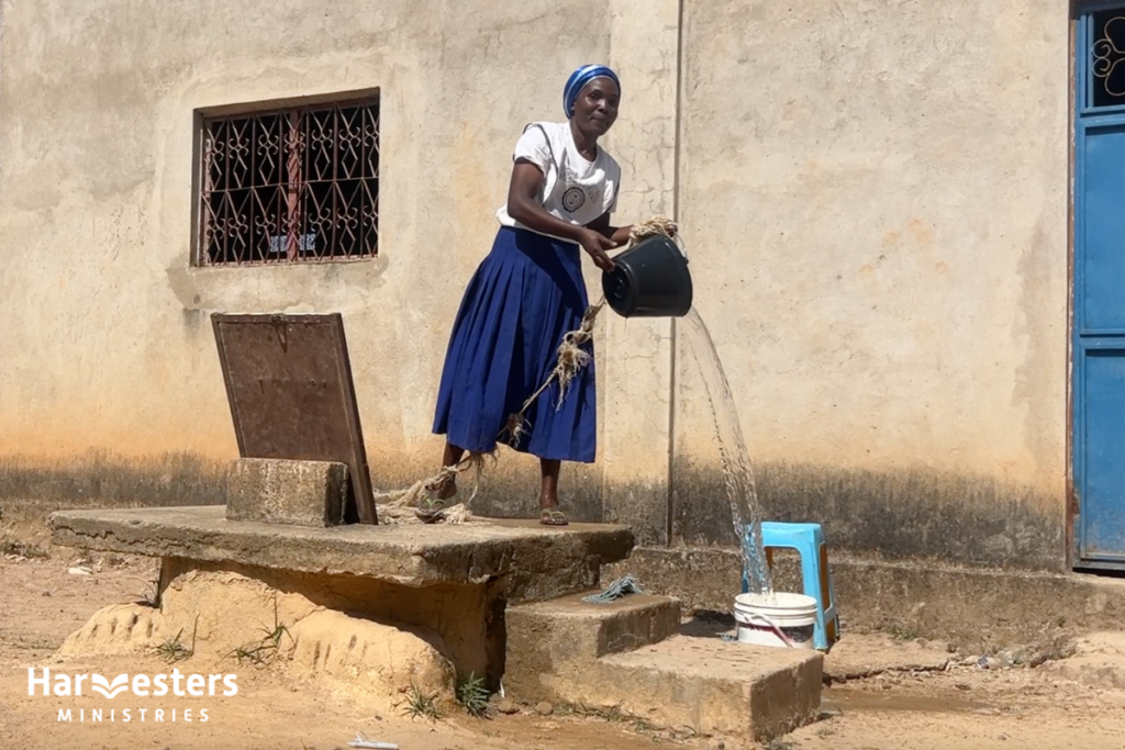 Woman collecting water from well. Harvesters Ministries